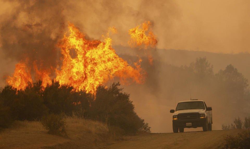 A truck passes by flames during the Ranch Fire.