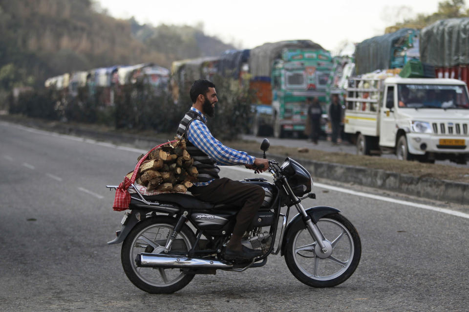 A man rides a motorbike carrying firewood, as trucks stand stranded on the main highway connecting Jammu and Srinagar, on the outskirts of Jammu, India, Saturday, Jan.28,2017. Heavy snowfall has cut off roads and disrupted power and communications in Kashmir, and hundreds of residents have been evacuated from high-risk areas. (AP Photo/Channi Anand )
