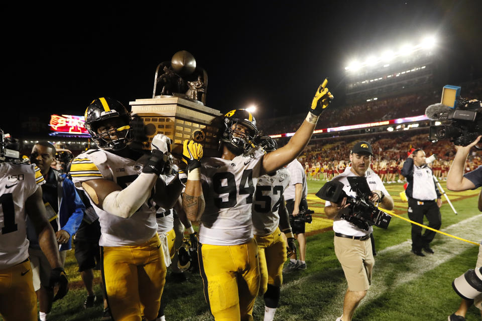 Iowa's Chauncey Golston, left, and A.J. Epenesa (94) carry the Cy-Hawk trophy off the field after the team's NCAA college football game against Iowa State, Saturday, Sept. 14, 2019, in Ames, Iowa. Iowa won 18-17. (AP Photo/Charlie Neibergall)