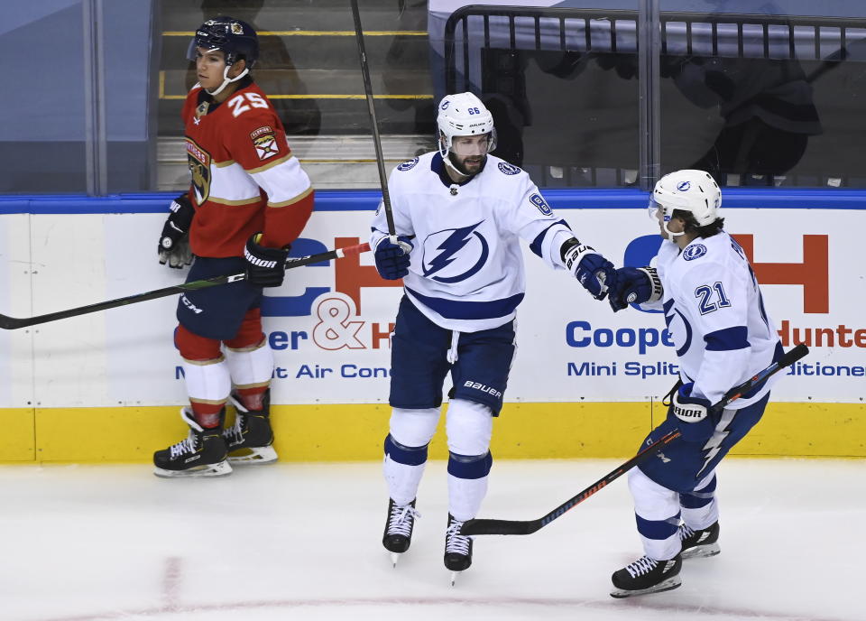 Tampa Bay Lightning right wing Nikita Kucherov (86) celebrates his goal with teammate Brayden Point (21) as Florida Panthers defenseman Brady Keeper (25) looks on during the third period of an exhibition NHL hockey game ahead of the Stanley Cup playoffs in Toronto on Wednesday, July 29, 2020. (Nathan Denette/The Canadian Press via AP)