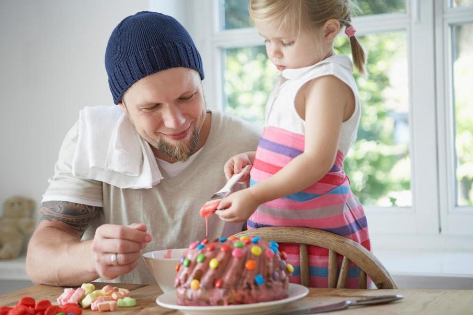 Father and daughter icing a cake.