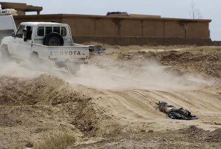 A vehicle belonging to Shi’ite militia fighters pulls the body of an Islamic State fighter, who was killed during clashes with Iraqi forces, in Tikrit April 1, 2015. REUTERS/Stringer