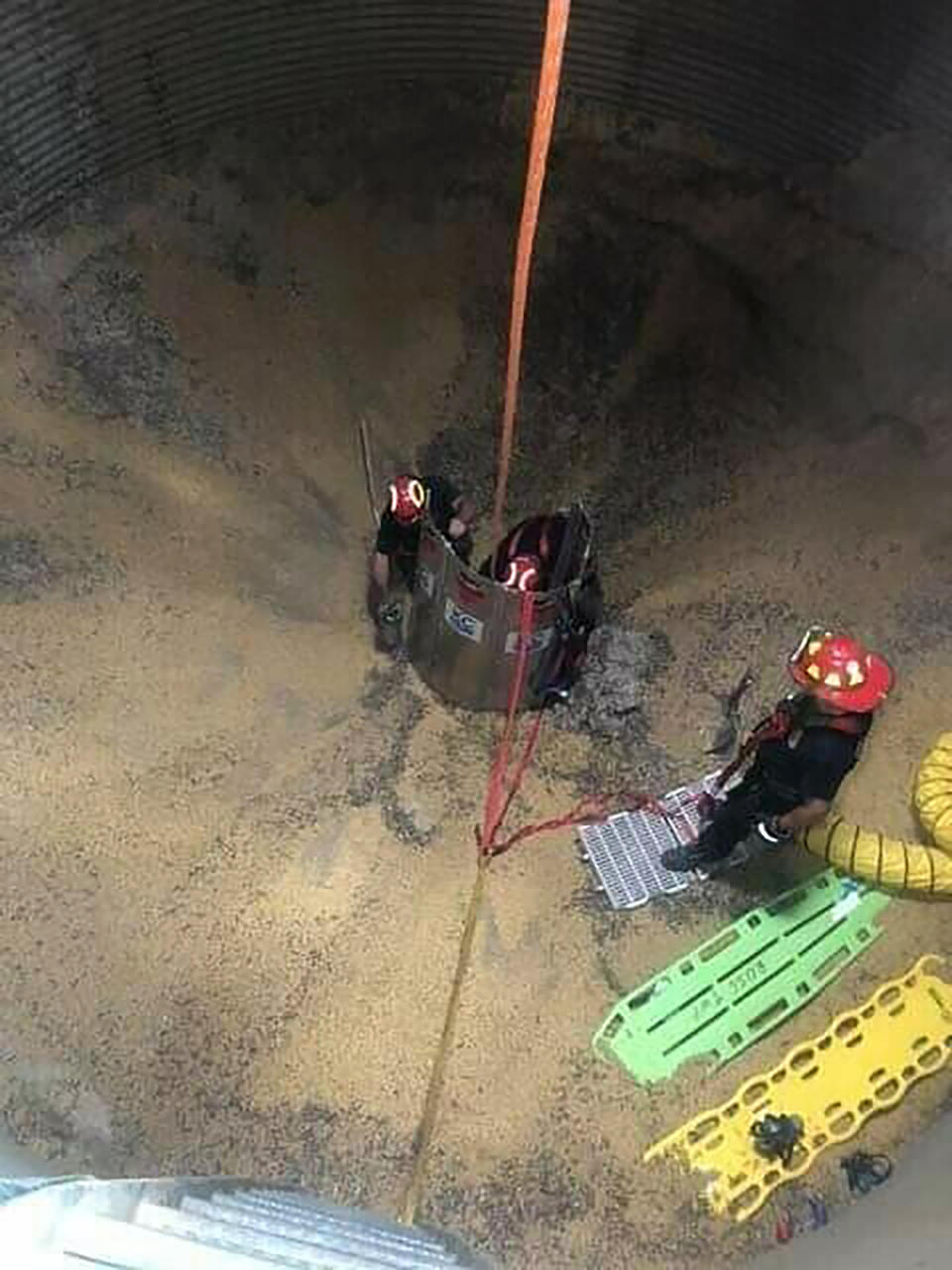 In this May 30, 2019 photo provided by the Ross Township Fire Department firefighters assemble a tube around farmer Jay Butterfield during the process of rescuing him from a soybean bin on his farm in Ross Township, Ohio. He became buried up to his neck while trying to break up clumps of soybeans in the bin. (Ross Township Fire Department via AP)