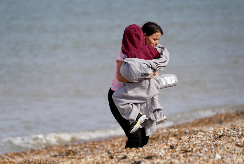 A woman and child thought to be migrants walk ashore in Dungeness, Kent (Gareth Fuller/PA) (PA Wire)