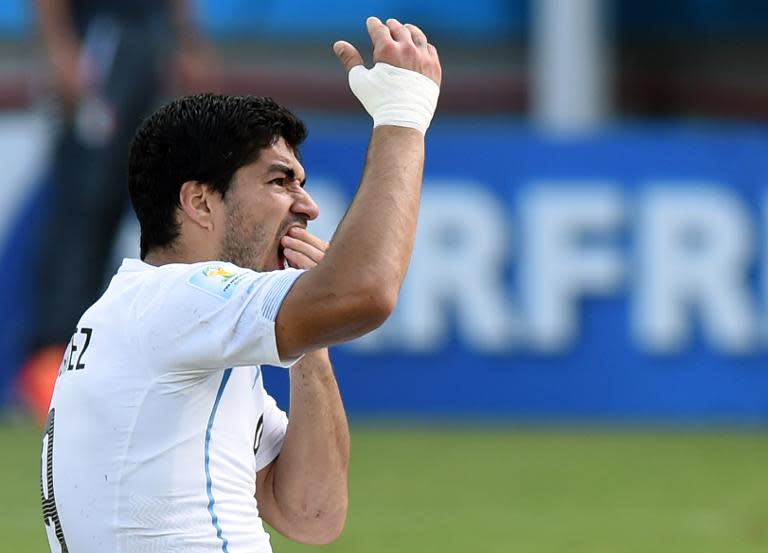 Uruguay forward Luis Suarez puts his hand to his mouth after clashing with Italy's defender Giorgio Chiellini during a Group D football match in Natal during the 2014 FIFA World Cup on June 24, 2014