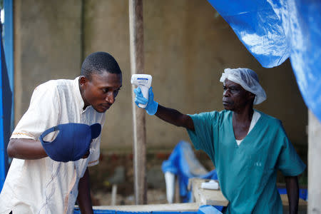 A health worker measures the temperature of a man entering the ALIMA (The Alliance for International Medical Action) Ebola treatment centre in Beni, in the Democratic Republic of Congo, April 1, 2019. Picture taken April 1, 2019. REUTERS/Baz Ratner