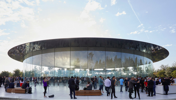 Apple's Steve Jobs Theater is shown with its rounded glass outer wall and a blue sky background