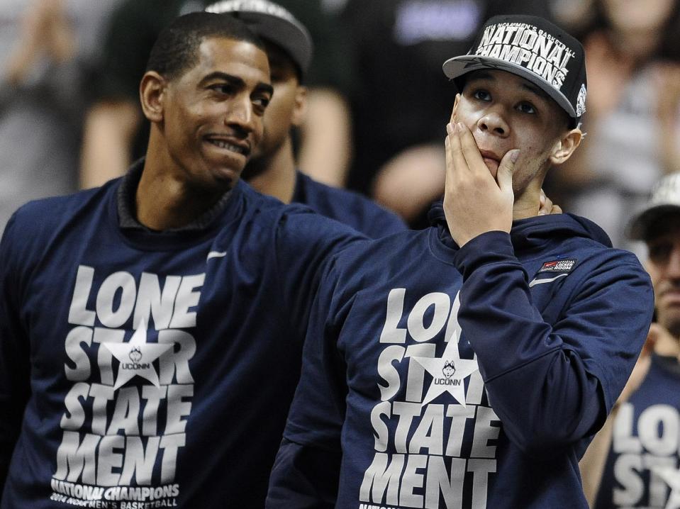Connecticut's Shabazz Napier, right, reacts as his name is revealed on the Huskies Wall of Honor as coach Kevin Ollie, left, looks over at Napier during a pep rally celebrating Connecticut's fourth NCAA men's basketball championship Tuesday, April 8, 2014, in Storrs, Conn. (AP Photo/Jessica Hill)
