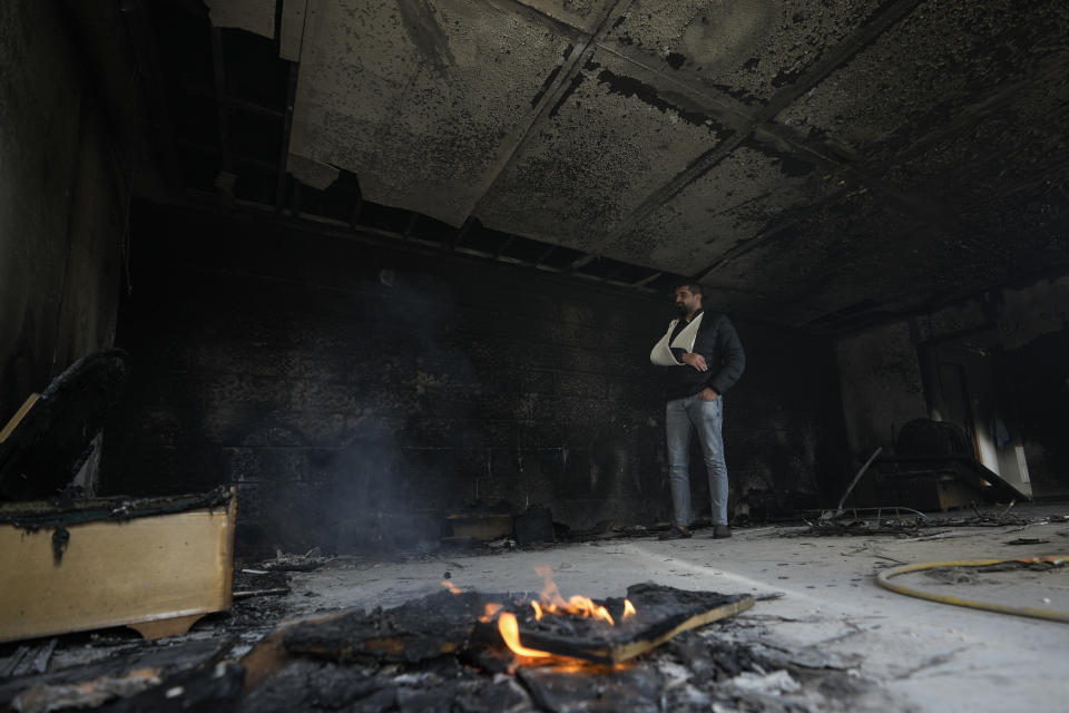 A Palestinian man looks at a damaged building in the town of Hawara, near the West Bank city of Nablus, Monday, Feb. 27, 2023. Scores of Israeli settlers went on a violent rampage in the northern West Bank, setting cars and homes on fire after two settlers were killed by a Palestinian gunman. Palestinian officials say one man was killed and four others were badly wounded. (AP Photo/Majdi Mohammed)