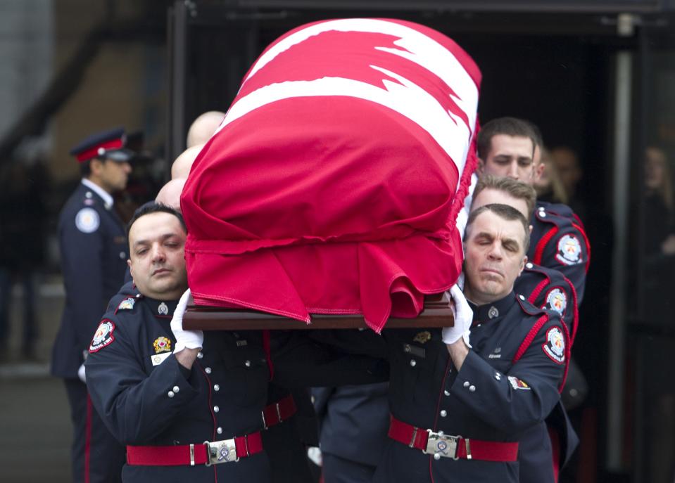 The casket of police constable John Zivcic is carried by the honor guard out of a public memorial in Toronto