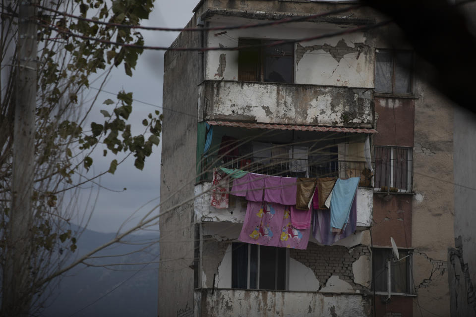 In this Wednesday, Nov. 27, 2019 photo, laundry hangs on a line from a damaged building in Thumane, western Albania following a deadly earthquake. A handbag dangles from a coat-hanger, gleaming saucepans sit stacked in a kitchen cabinet, sheets and duvets lie neatly folded in a bedroom cupboard. All scenes of ordinary domesticity, except for one detail: the rest of the homes these ordinary items were part of have vanished, crumpling in the devastating force of an earthquake that struck Albania earlier this week.(AP Photo/Petros Giannakouris)