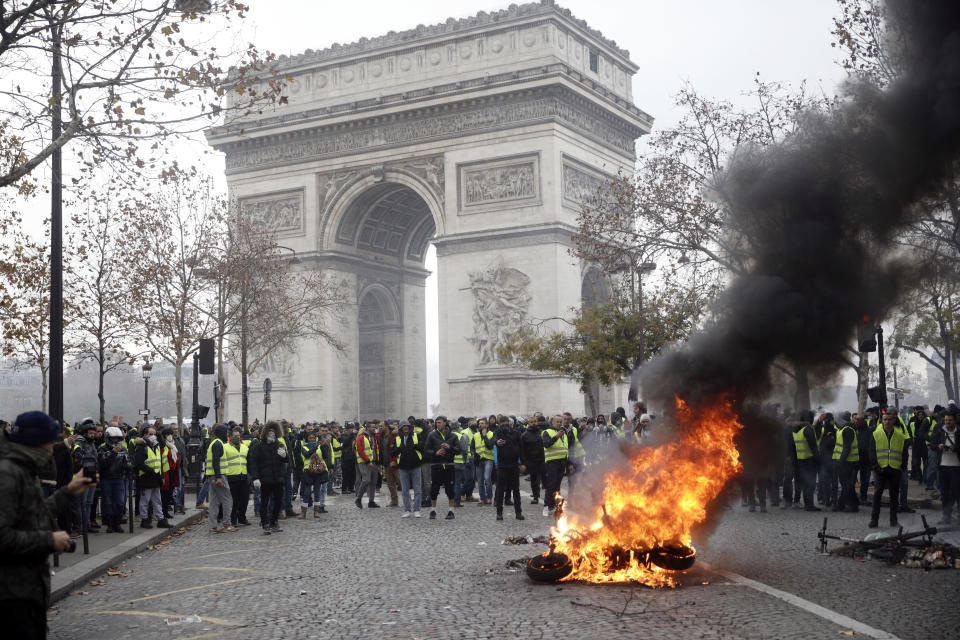 A motorcycle burns in front of protestors at the Arc de Triomphe. Source: AP