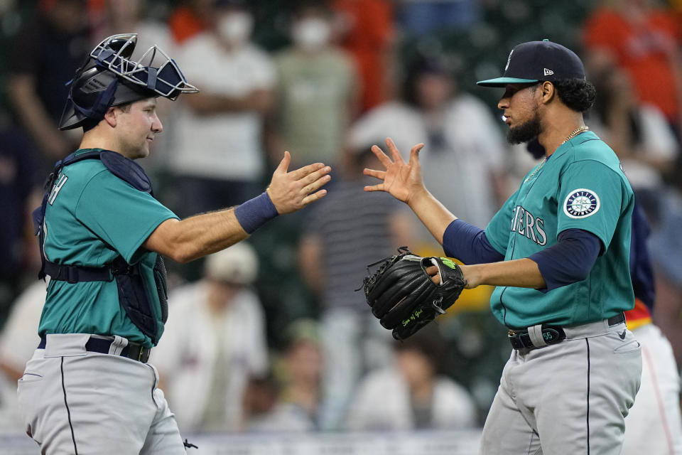 Seattle Mariners relief pitcher Yohan Ramirez, right, celebrates with catcher Cal Raleigh after a baseball game against the Houston Astros Sunday, Aug. 22, 2021, in Houston. The Mariners won 6-3 in 11 innings. (AP Photo/David J. Phillip)