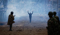 <p>AUG. 10, 2017 – A man seeking safety walks with his hands in the air through a thick cloud of tear gas towards riot police, as they clash with protesters throwing rocks in the Kawangware slum of Nairobi, Kenya. International observers on urged Kenyans to be patient as they awaited final election results following opposition allegations of vote-rigging, but clashes between police and protesters again erupted in Nairobi. (Photo: Ben Curtis/AP) </p>