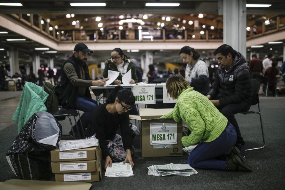 Electoral officials count ballots after the closing of a nationwide referendum seeking to curb corruption in Bogota, Colombia, Sunday, Aug. 26, 2018. Voters were asked to approve seven proposals that referendum supporters hope will bring about tougher anti-corruption legislation, but the referendum will only be valid if a third of all voters take part. (AP Photo/Ivan Valencia)