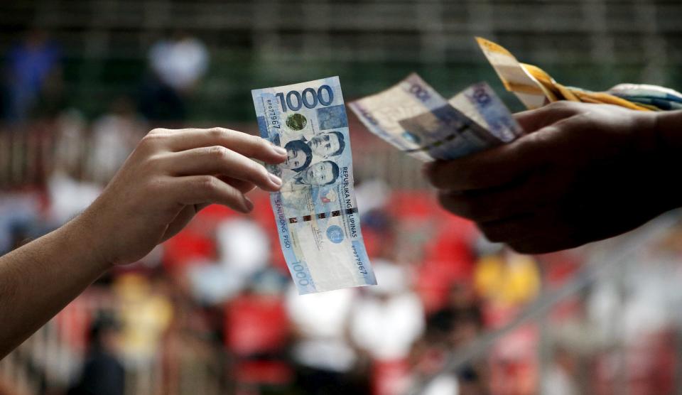 A gambler who lost a cockfighting bet, pays his wager inside an arena in Angeles city, north of Manila, Philippines March 11, 2015. Cockfighting has a long history in the Philippines, dating back years prior to the country's Spanish colonisation in 1521. It remains a hugely popular form of gambling. When paying your final respects for a relative or friend, the last thing you might expect to see at the wake is people placing bets on a card game or bingo. Not in the Philippines. Filipinos, like many Asians, love their gambling. But making wagers on games such as "sakla", the local version of Spanish tarot cards, is particularly common at wakes because the family of the deceased gets a share of the winnings to help cover funeral expenses. Authorities have sought to regulate betting but illegal games persist, with men and women, rich and poor, betting on anything from cockfighting to the Basque hard-rubber ball game of jai-alai, basketball to spider races. Many told Reuters photographer Erik De Castro that gambling is only an entertaining diversion in a country where two-fifths of the population live on $2 a day. But he found that some gamble every day. Casino security personnel told of customers begging to be banned from the premises, while a financier who lends gamblers money at high interest described the dozens of vehicles and wads of land titles given as collateral by those hoping lady luck would bring them riches. REUTERS/Erik De Castro PICTURE 8 OF 29 FOR WIDER IMAGE STORY "HIGH STAKES IN MANILA". SEARCH "BINGO ERIK" FOR ALL IMAGES.