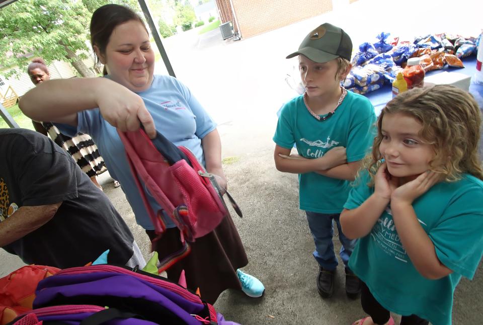 Jacqueline Mullaly hands out backpacks to nine-year-old Tyler Collier and his sister, six-year-old Tilliie Collier, during the annual Back to School Bash Saturday morning, July 22, 2023, at the Cherryville Church of God.