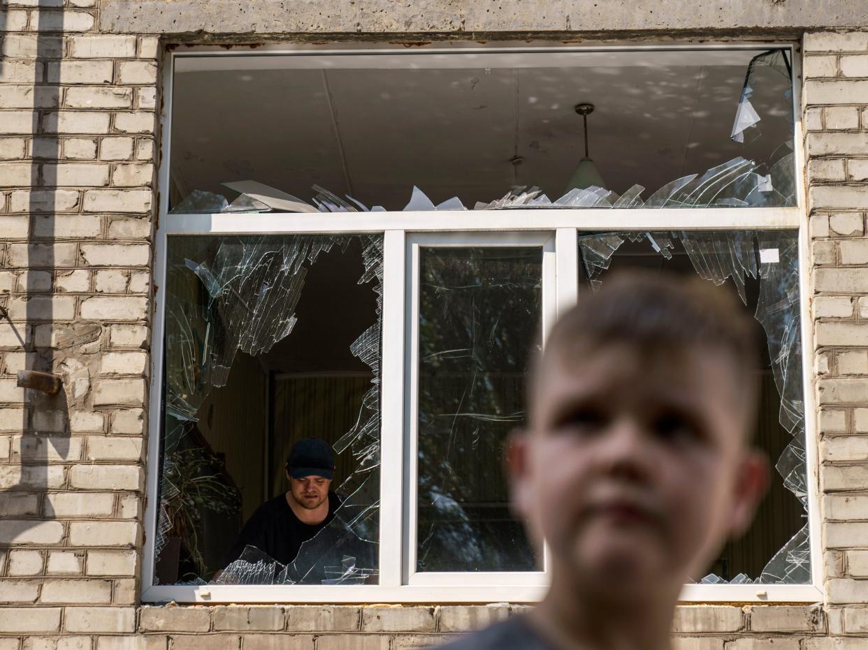 A worker cleans up inside as Tikhon Pavlov, 11, walks past the Kramatorsk College of Technologies and Design, where he used to take karate lessons, after an early morning rocket attack in Kramatorsk, Donetsk region, eastern Ukraine, Friday, Aug. 19, 2022. Russia continued to shell towns and villages in Ukraine's embattled eastern Donetsk region, according to regional authorities, where Russian forces are pushing to overtake areas still held by Ukraine.