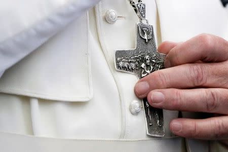 Pope Francis touches his crucifix as he talks to journalists during a press conference on his return flight from Cairo to Rome April 29, 2017. REUTERS/Gregorio Borgia/Pool