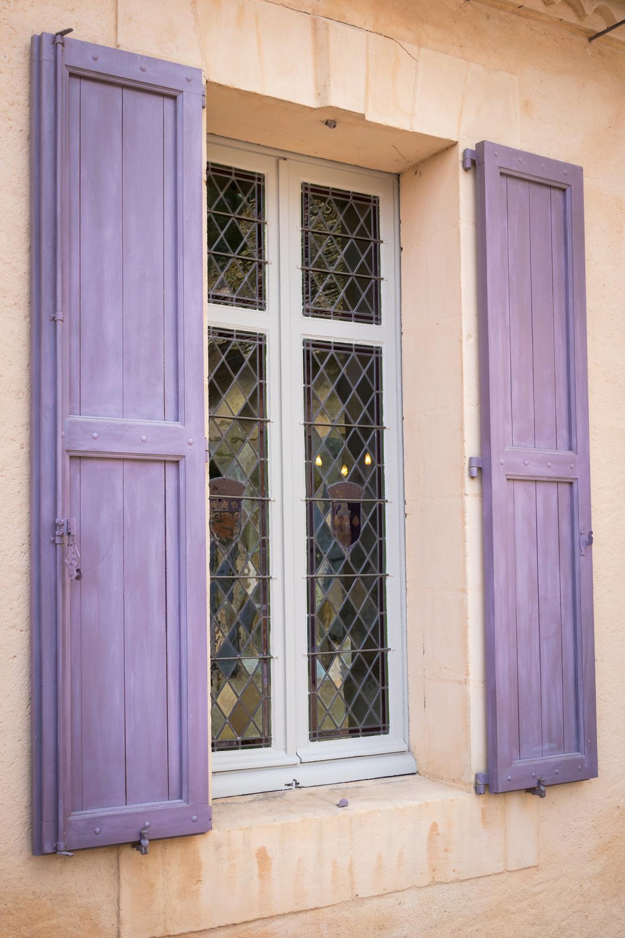 window with purple shutters in an old facade in Mediterranean style