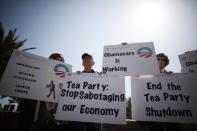 Demonstrators hold up signs at an education and awareness event on the Affordable Care Act and protest against Tea Party officials they say are threatening an economic shutdown, in Santa Monica, California October 10, 2013. (REUTERS/Lucy Nicholson)