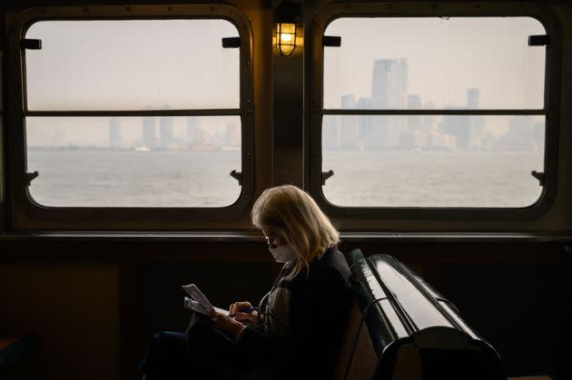 A passenger wearing a face mask rides the Staten Island Ferry past the Manhattan skyline during heavy smog in New York on Tuesday.
