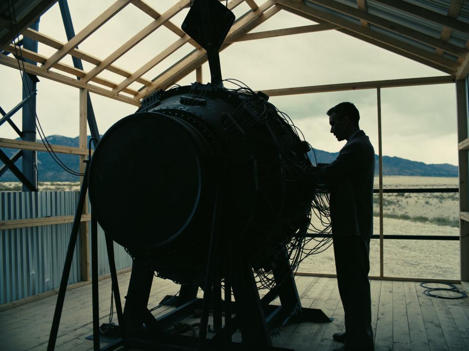 Cillian Murphy standing next to atomic bomb