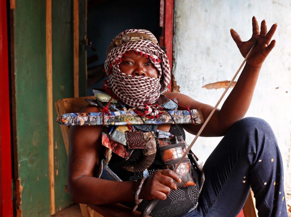 A masked female member of the anti-balaka, a Christian militia, holds a machete as she sits in a village of Zawa