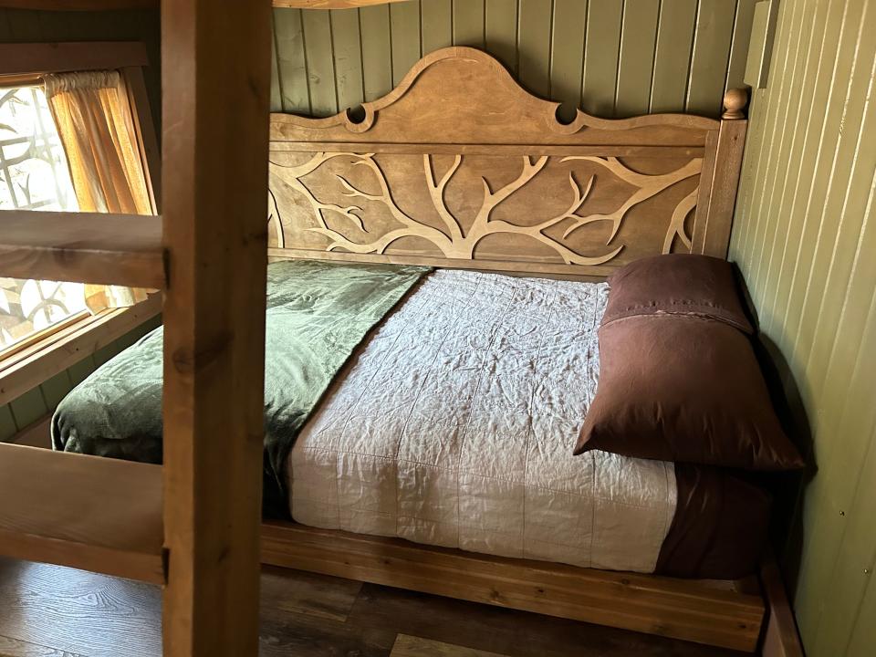 second floor bed with green comforter and tree headboard