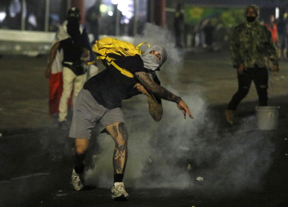 Manifestantes lanzando bombas lacrimógenas en protestas 