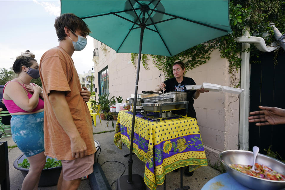 In this Wednesday, Sept. 1, 2021, photo, El Pavo Real restaurant owner Lindsey McLellan, right, used food preserved "with ice and prayer" to serve up a free steak taco meal, in New Orleans, La. In New Orleans, food is just one of the many ways that residents help each other during hard times. And it's been no different in the days after Hurricane Ida, which flooded or destroyed homes, tore up trees and knocked out the entire city's power grid. (AP Photo/Eric Gay)