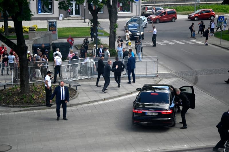 Bodyguards take Slovakian Prime Minister Robert Fico to safety in a car from the scene of the incident. Fico had been shot and injured after a cabinet meeting in the town of Handlova. Radovan Stoklasa/TASR/dpa
