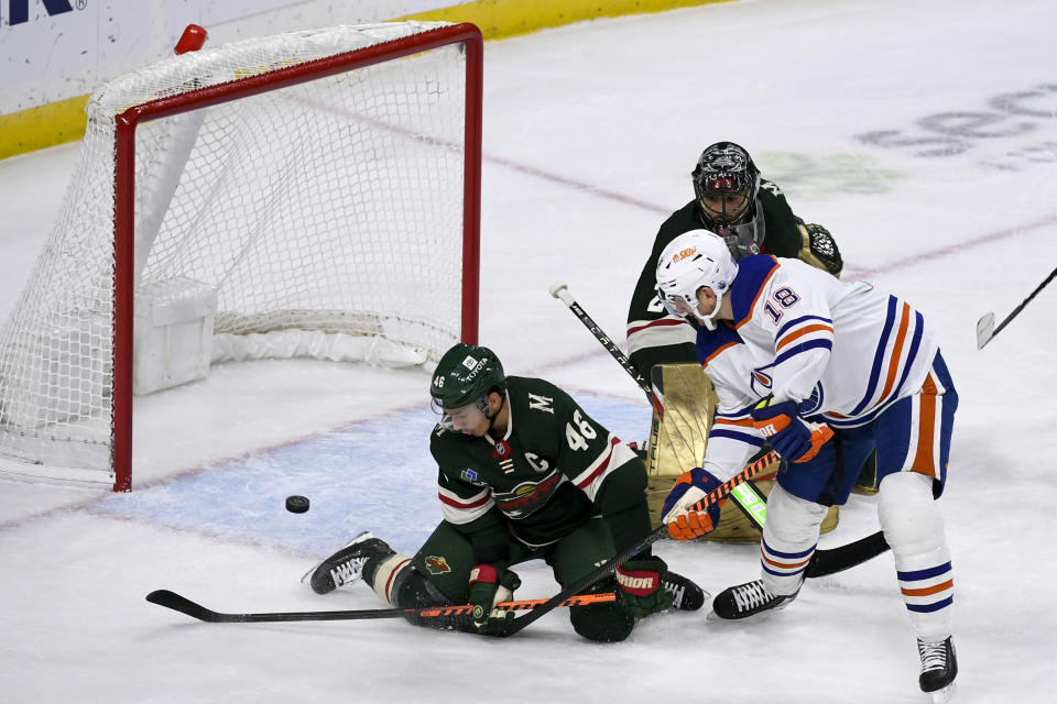 A shot by Edmonton Oilers center Zach Hyman (18) gets past Minnesota Wild defenseman Jared Spurgeon (46) for a goal as Wild goalie Marc-Andre Fleury. upper right, looks on during the first period of an NHL hockey game Monday, Dec. 12, 2022, in St. Paul, Minn. (AP Photo/Craig Lassig)