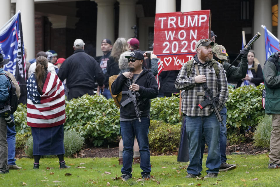 FILE - In this Jan. 6, 2021 file photo, two men stand armed with guns in front of the Governor's Mansion in Olympia, Wash., during a protest supporting President Donald Trump and against the counting of electoral votes in Washington, D.C., affirming President-elect Joe Biden's victory. After a 2020 election cycle dominated by conspiracy theories and false claims about voting, top election officials across the country are looking ahead to future elections and grappling with how they can counter a wave of misinformation that led to violent threats against them and ultimately a deadly riot at the Capitol. (AP Photo/Ted S. Warren, File)