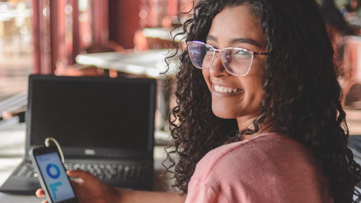 Portrait of young woman using financial app on smartphone.