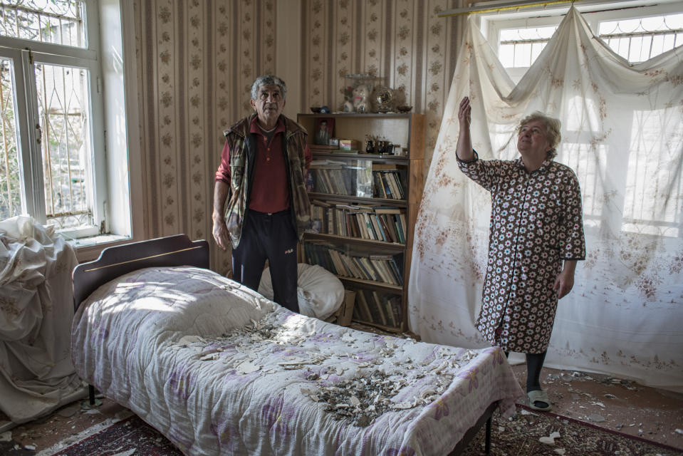 Nazile Tehmezova, right, and her husband Ramiz Huseyinov inspect the damage to their house following overnight shelling by Armenian forces, in the city of Terter, Azerbaijan, Thursday, Oct. 15, 2020. The conflict between Armenia and Azerbaijan continues for a third week despite a Russia-brokered cease-fire deal, as both sides exchanged accusations and claims of new attacks over the separatist territory of Nagorno-Karabakh. (Can Erok/DHA via AP)