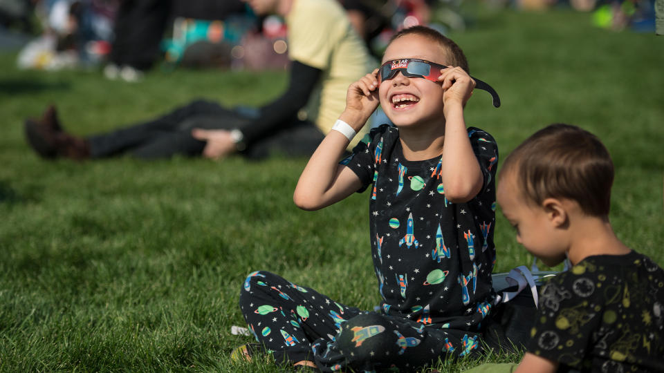 A boy watches the total solar eclipse through protective glasses in Madras, Oregon on Monday, Aug. 21, 2017.
