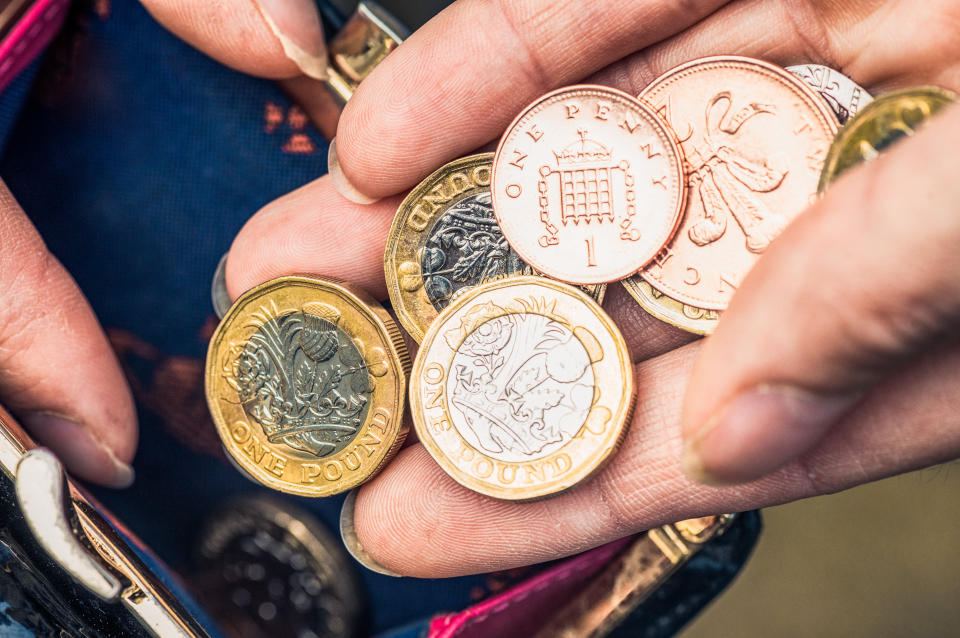 Close-up of a woman's hand holding one pound coins and other change from her purse. bills