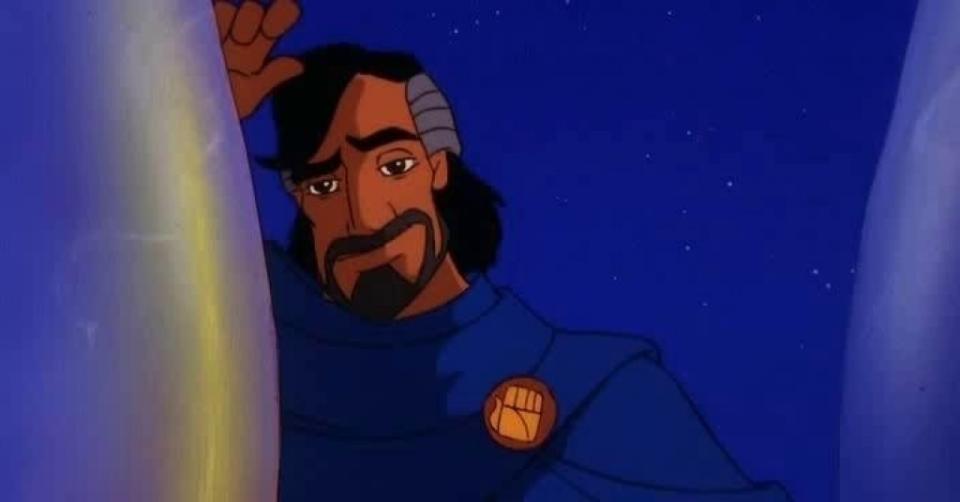 Prince of Egypt character Jethro in a calm expression, wearing a blue robe with a rounded brooch depicting a closed fist