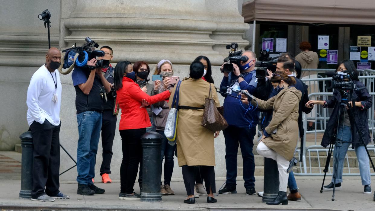 A city employee returning to work is the main attraction of reporters and camera crews  outside the David Dinkins Municipal Building in downtown Manhattan early Monday, May 3. 