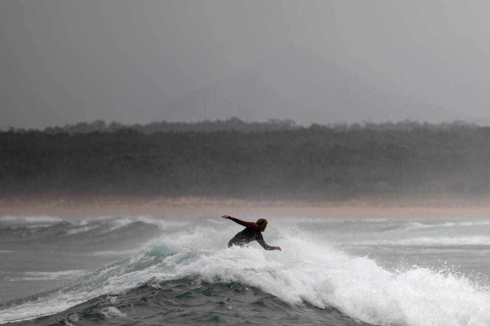 A surfer rides a wave in Bengello beach in Broulee