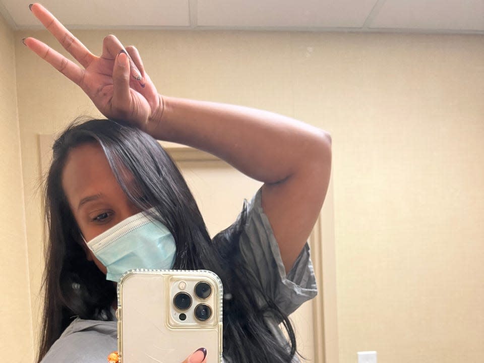 Avi Grant-Noonan in a hospital gown, taking a mirror selfie.