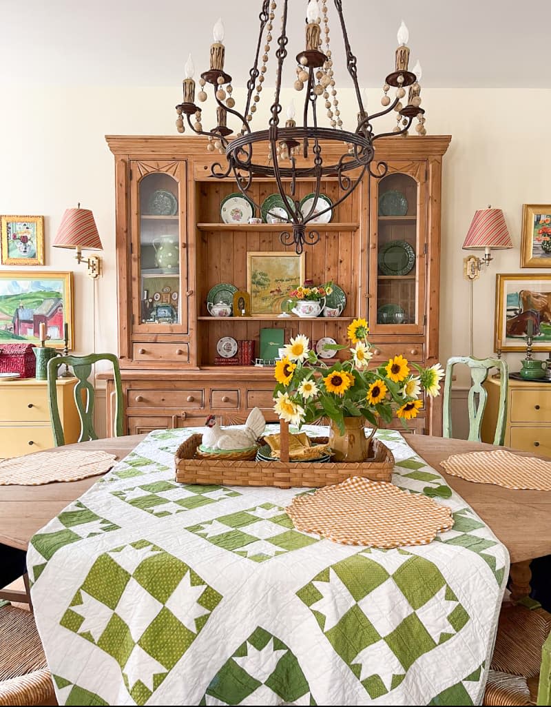 Sunflowers on table decorated with green and white quilt.