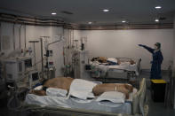 A healthcare worker gestures as she assists COVID-19 patients at a library that was turned into an intensive care unit (ICU) at Germans Trias i Pujol hospital in Badalona, Barcelona province, Spain, Wednesday, April 1, 2020. The new coronavirus causes mild or moderate symptoms for most people, but for some, especially older adults and people with existing health problems, it can cause more severe illness or death. (AP Photo/Felipe Dana)