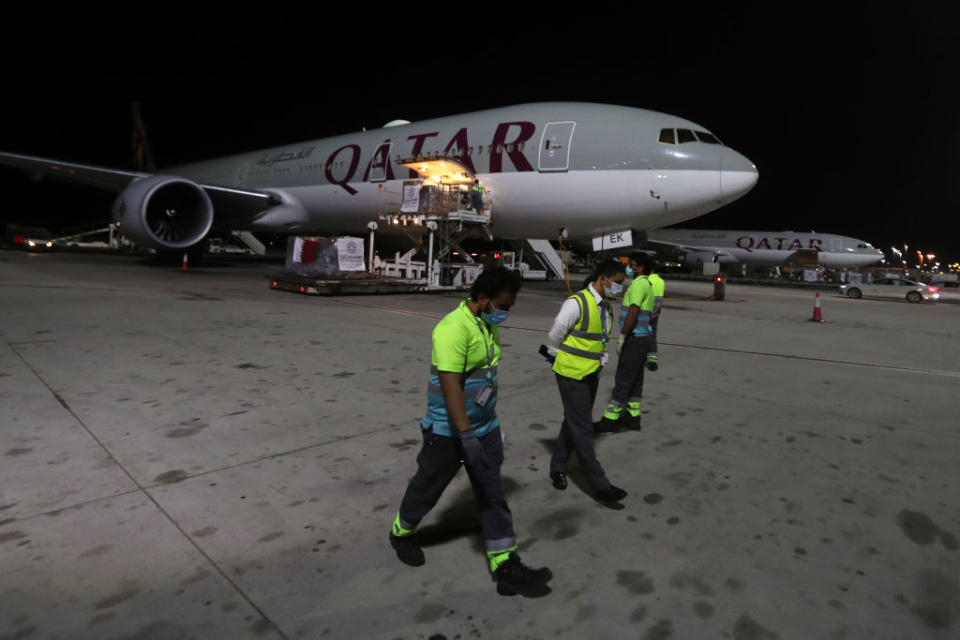 Airport workers wear masks as supplies to tackle coronavirus are loaded onto a Qatar Airways flight at Doha's Hamad International Airport. Source: Getty