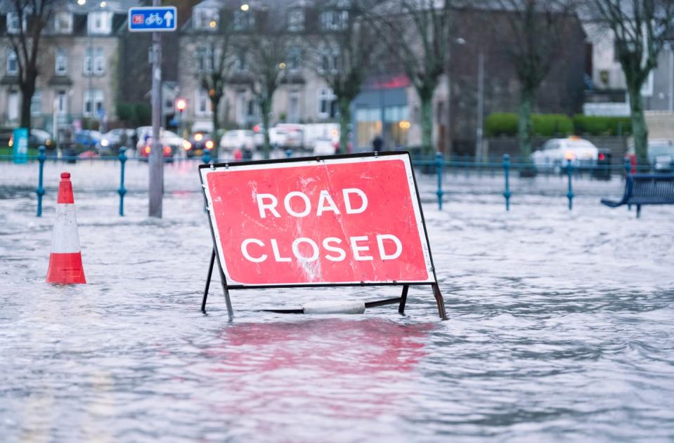 road flood closed sign under deep water during bad extreme heavy rain storm weather uk