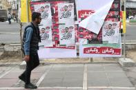 A man walks past parliamentary election campaign posters in Tehran