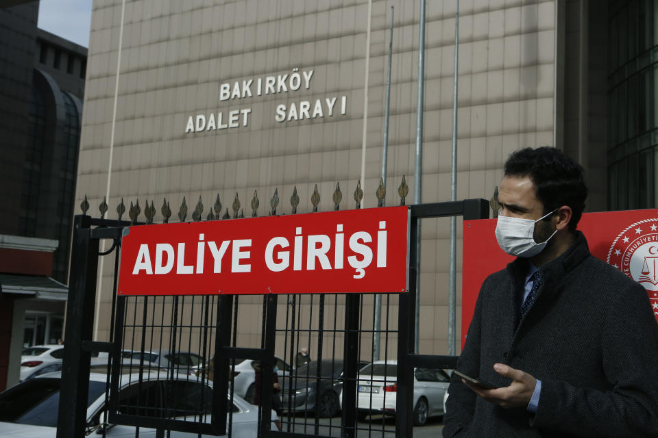 An unidentified person stands outside the courthouse during the third hearing in the trial of Carlos Ghosn, former Nissan Motor Co. chairman, in Istanbul, Wednesday, Jan. 20, 2021. Turkish prosecutors on Wednesday pushed for maximum 12 years in prison each for a Turkish private airline company official and two pilots who are accused of smuggling Ghosn out of Japan, Turkey's state-run news agency reported.(AP Photo/Mehmet Guzel)