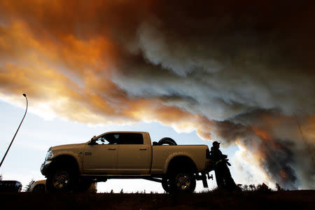 FILE PHOTO -- People wait at a roadblock as smoke rises from wildfires near Fort McMurray, Alberta, Canada, May 6, 2016. REUTERS/Chris Wattie/File Photo