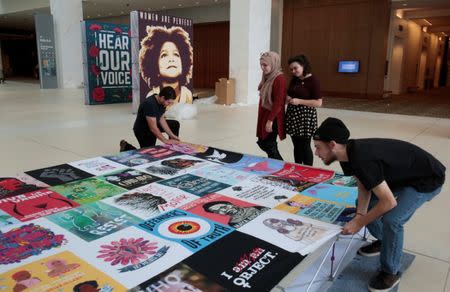 Isra Chaker and Martha Neuman watch as a display of social justice images is assembled before the start of the three-day Women's Convention at Cobo Center in Detroit, Michigan, U.S., October 26, 2017. REUTERS/Rebecca Cook